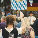 Girl in Crowd Holding Up a Mug of Beer at Oktoberfest