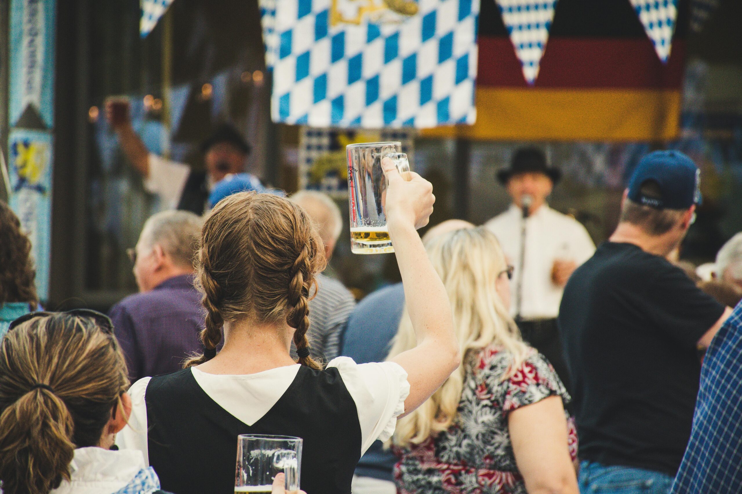 Girl in crowd holding up a mug of beer at Oktoberfest