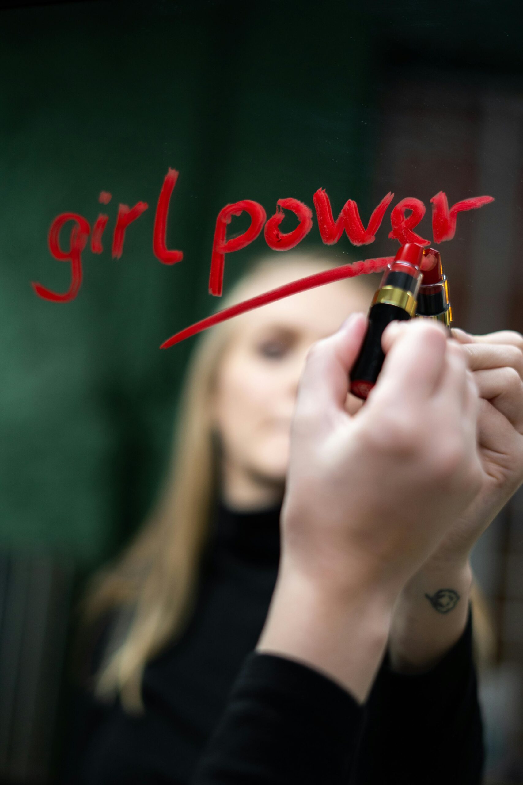 Woman writing on a mirror with lipstick Girl Power