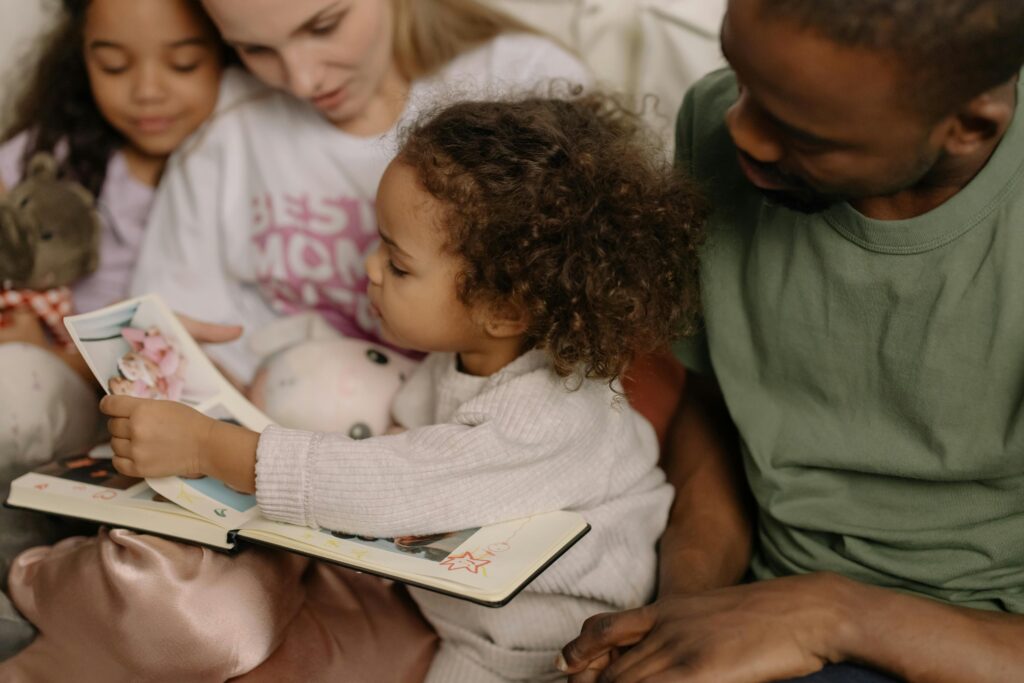 Little Girl Looking As a Book on a Mans Lap