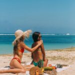 Two Girls on a Beach Applying Tanning Lotion