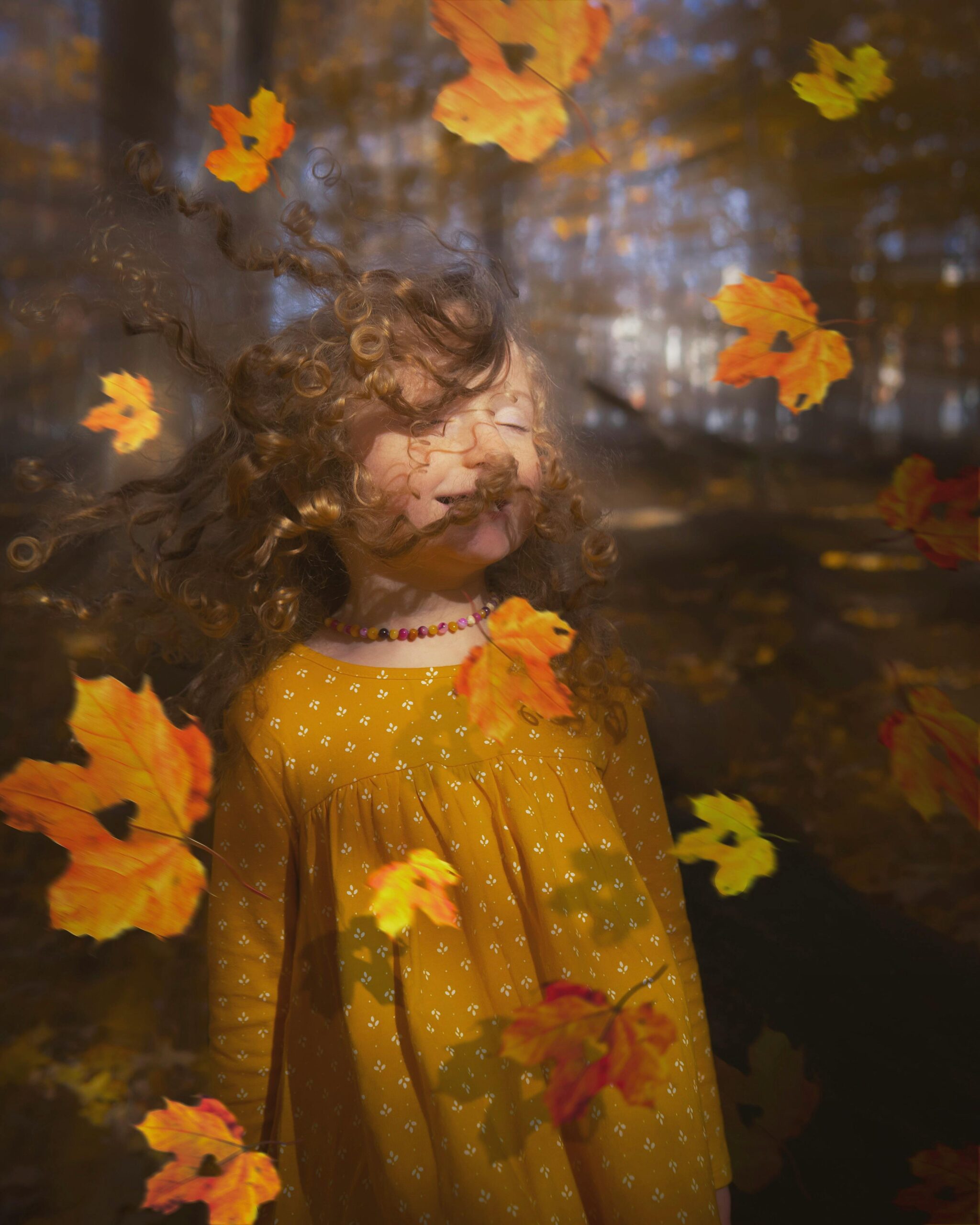 Little girl looking out the window at falling leaves