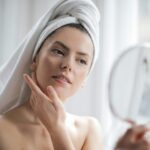 Woman Looking in Mirror Touching Skin