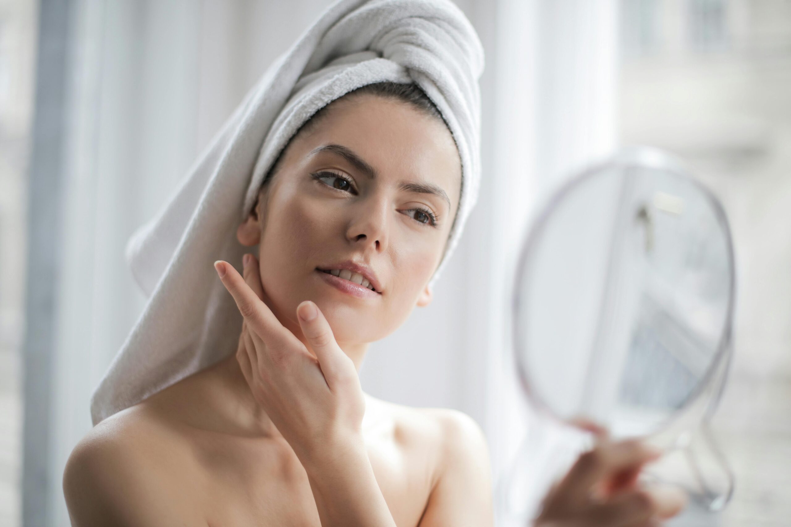 Woman looking in mirror touching skin