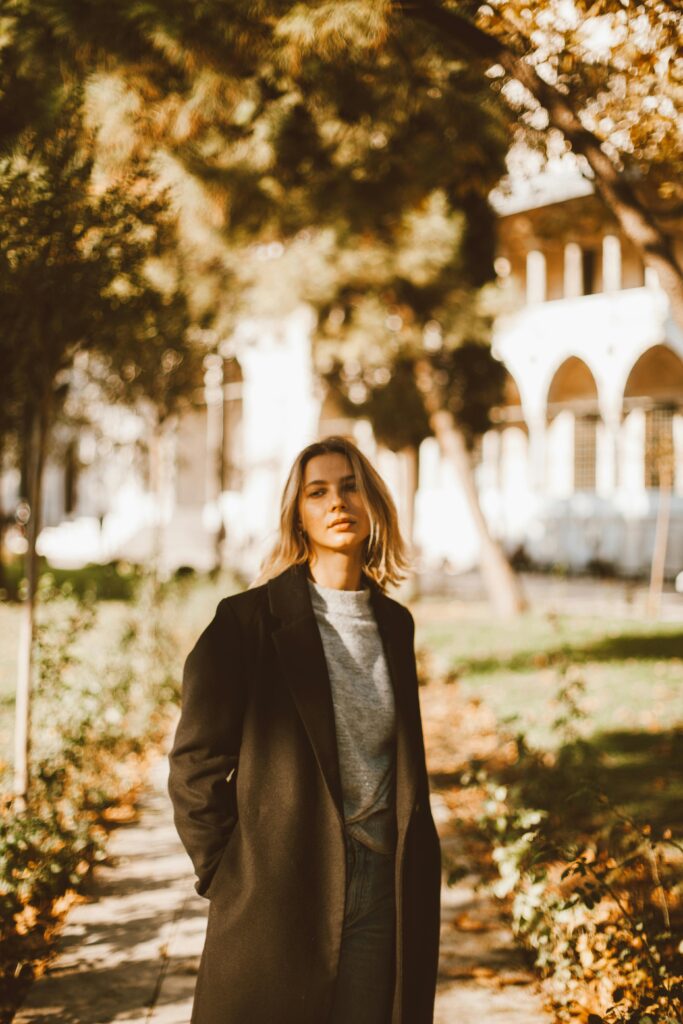 Woman Wearing a Jacket Standing on a Path with Fall Leaves