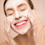 Woman Smiling While She Washes Her Face