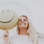 Smiling Woman Holding a Smiley Face Balloon