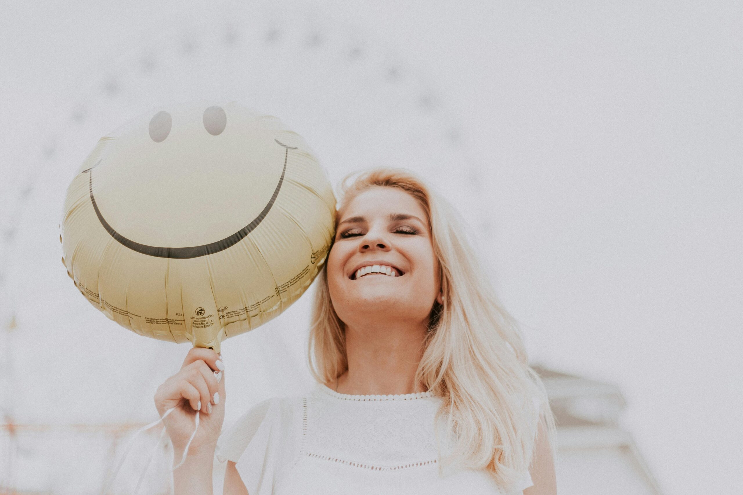 smiling woman holding a smiley face balloon