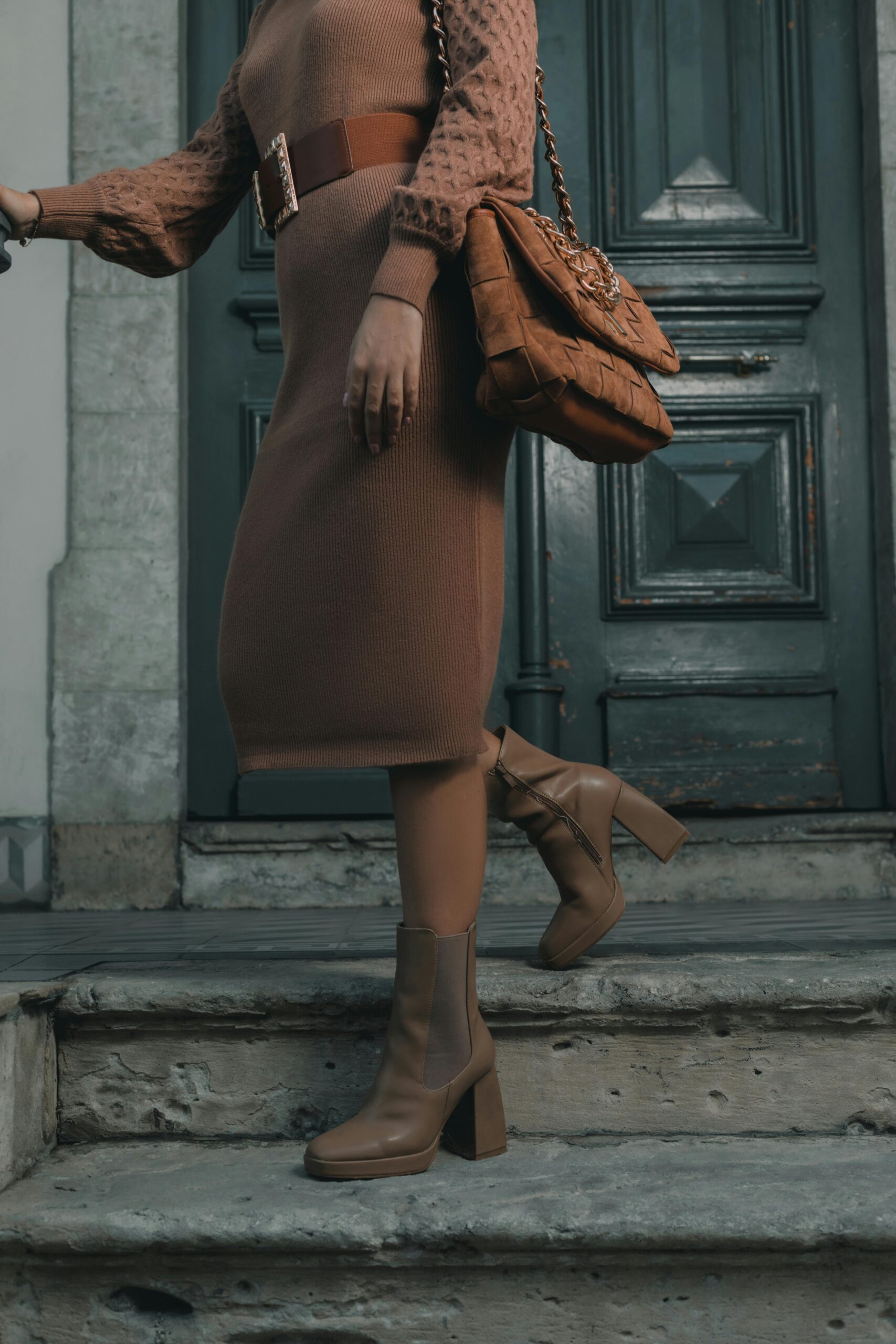 Woman wearing a dress and boots with a handbag